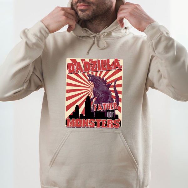 A man wearing a beige hoodie with a graphic design featuring a large purple monster and the text "DADZILLA FATHER OF MONSTERS" printed on it.