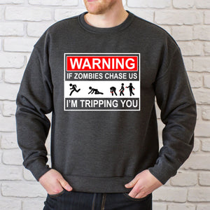 a man wearing a grey sweatshirt with a graphic design on it. The design includes a warning message about zombies chasing people and tripping them.