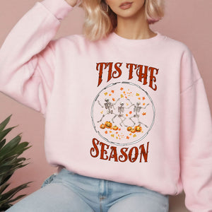 A woman wearing a pink sweatshirt with a Halloween-themed graphic design.