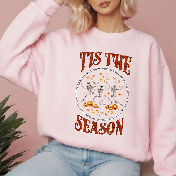 A woman wearing a pink sweatshirt with a Halloween-themed graphic design.