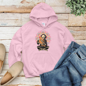 A pink hoodie with a graphic of a skeleton holding a guitar is displayed on a wooden surface, accompanied by a pair of jeans and a pair of shoes.