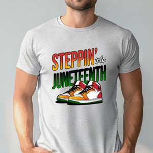 A man wearing a gray t-shirt with a graphic design featuring a pair of colorful sneakers and the text "StepPIN' into JUNEFTH".