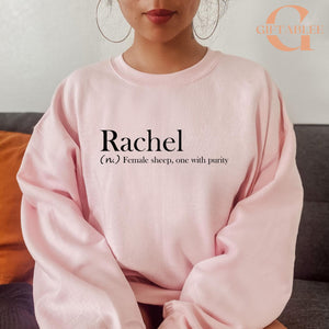 A woman wearing a pink sweatshirt with the word "Rachel" printed on it.