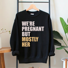 A black sweatshirt with white text printed on it, hanging on a wooden hanger.