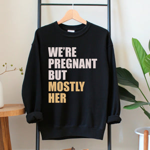 A black sweatshirt with white text printed on it, hanging on a wooden hanger.