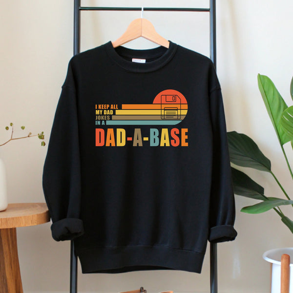 A black sweatshirt with a graphic design on it, hanging on a wooden hanger.