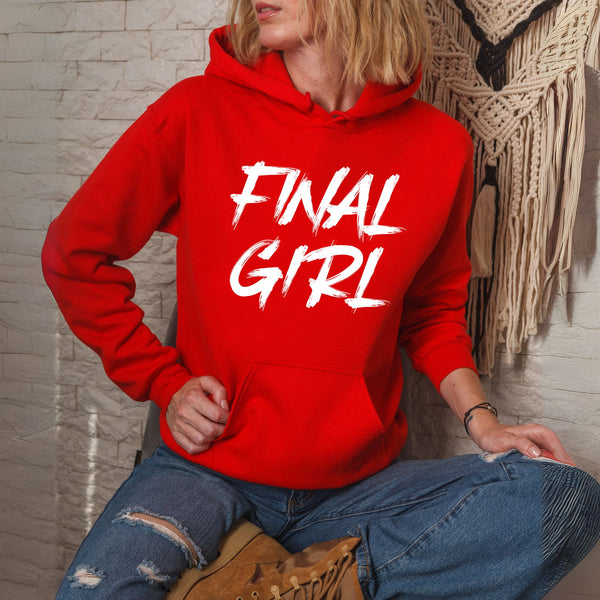 A person wearing a red hoodie with the text "FINAL GIRL" printed on it, sitting on a chair against a white brick wall.