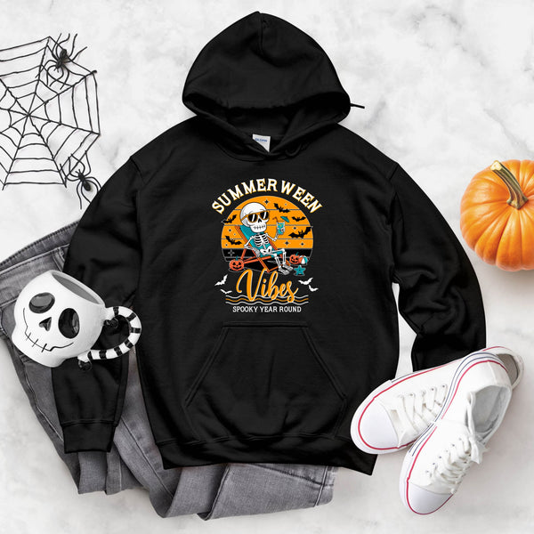 A black hoodie with a graphic design featuring a skeleton riding a skateboard and the text "Summer Week Vibes" is displayed on a white surface.
