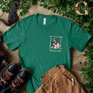 a green t-shirt with a graphic design, a pair of brown pants, and a pair of black shoes, all laid out on a surface with some greenery.