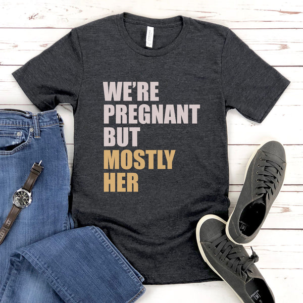 A gray t-shirt with text printed on it, along with a pair of jeans and sneakers, all laid out on a wooden surface.