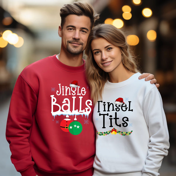 A man and a woman are standing together, both wearing Christmas-themed sweatshirts. The man's sweatshirt has the text "Jingle Balls" and the woman's sweatshirt has the text "Tinsel Tits".