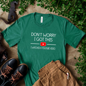 a green t-shirt with a humorous text printed on it, along with a pair of black shoes and some greenery.