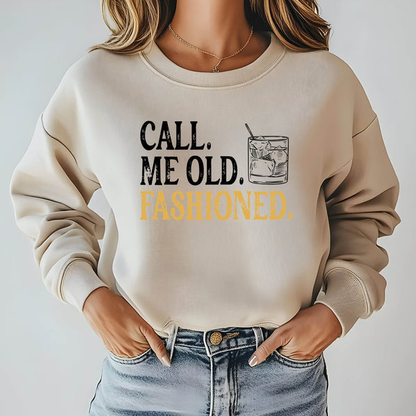 A woman wearing a beige sweater with the text "Call me old. Fashioned." printed on it.