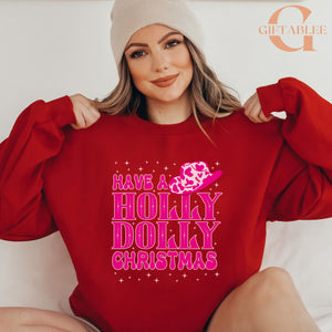 A woman wearing a red sweater with a pink and white design and text on it, posing with her arms behind her back.