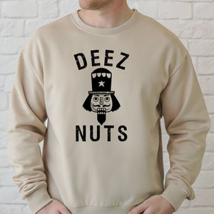 A man wearing a sand sweater with a graphic design that says "DEEZ NUTS" and features a nutcracker or nutcracker-like character.