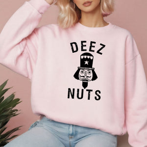 A woman wearing a pink sweatshirt with a graphic design featuring a nutcracker and the text "DEEEZ NUTS".