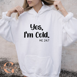 A person wearing a white hoodie with the text "Yes, I'm Cold. ME 24:7" printed on it.