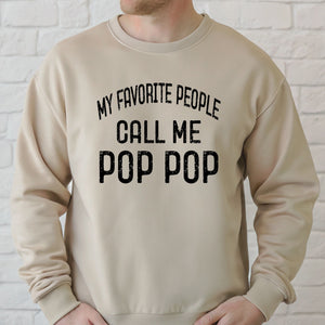 A man wearing a beige sweater with the text "MY FAVORITE PEOPLE CALL ME POP POP" printed on it.