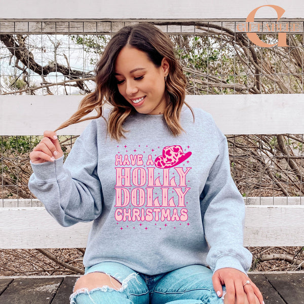 A woman wearing a gray sweatshirt with a pink and white design and text, sitting on a bench in front of a fence.