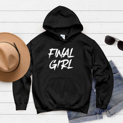 A black hoodie with the text "FINAL GIRL" printed on it, along with a pair of sunglasses and a hat, all laid out on a white background.
