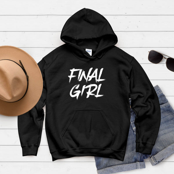 A black hoodie with the text "FINAL GIRL" printed on it, along with a pair of sunglasses and a hat, all laid out on a white background.