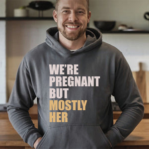 A man wearing a gray hoodie with text printed on it, smiling at the camera.
