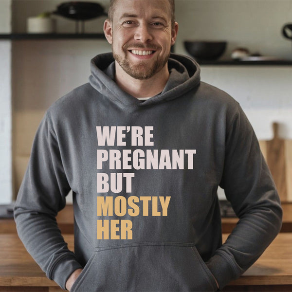 A man wearing a gray hoodie with text printed on it, smiling at the camera.