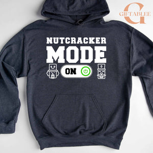 A gray hoodie with a graphic design that says "NUTCRACKER MODE ON" and two small robot icons.
