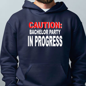 A navy blue hoodie with the text "CAUTION: BACCHELOR PARTY IN PROGRESS" printed on it.