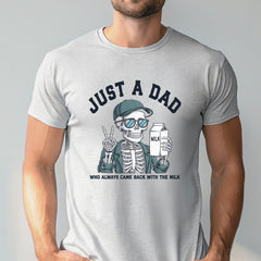 A man wearing a gray t-shirt with a graphic design depicting a skeleton wearing sunglasses and holding a carton of milk, with the text "Just a Dad" above the image.