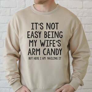 A man wearing a beige sweater with a humorous text printed on it.
