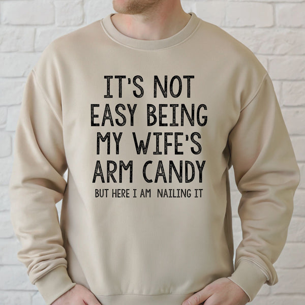 A man wearing a beige sweater with a humorous text printed on it.