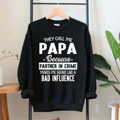 A black sweatshirt with white text that reads "They call me PAPA because Partner in crime makes me sound like a bad influence".