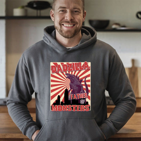 A man wearing a grey hoodie with a graphic design featuring a large red and yellow graphic of a Godzilla-like creature and the text "DADZILLA FATHER OF MONSTERS".