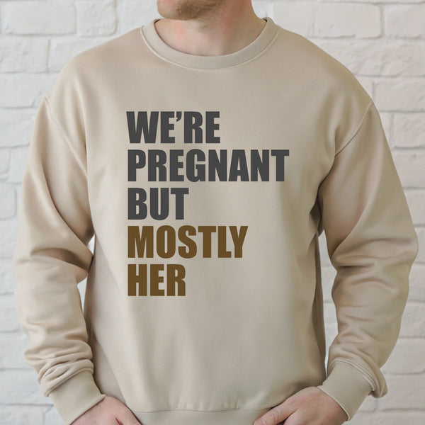 A man wearing a beige sweater with text printed on it.
