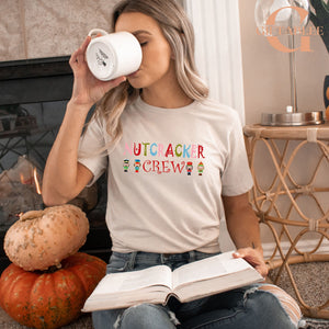 A woman is sitting on the floor, reading a book and drinking from a mug, with a pumpkin and a nutcracker figurine nearby.