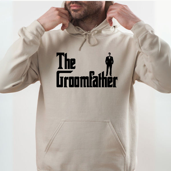 A man wearing a beige hoodie with the text "The Groomfather" printed on it.