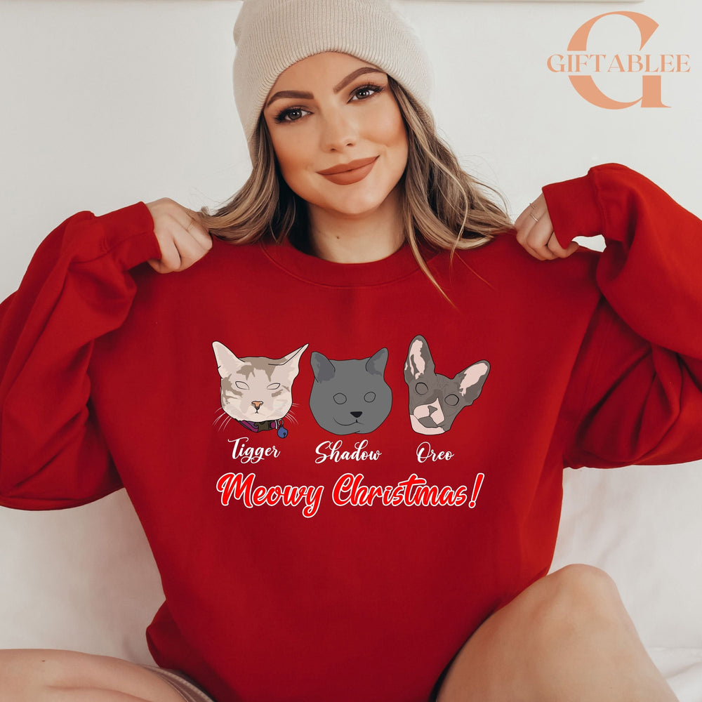 A woman wearing a red sweater with a graphic of three cats and the text "Meowy Christmas!" printed on it.