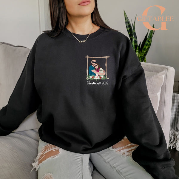 A woman wearing a black sweatshirt with a graphic design on the front, sitting on a couch.