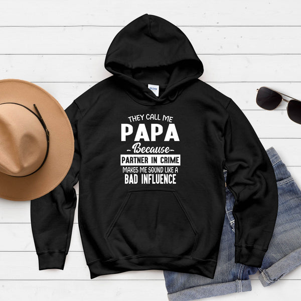 A black hoodie with a humorous text printed on it, along with a pair of sunglasses and a hat, all laid out on a white background.