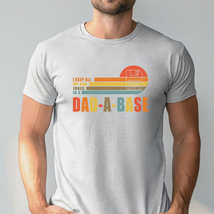 A man wearing a gray t-shirt with a graphic design that says "I keep all my dad jokes in a Dad-A-Base".