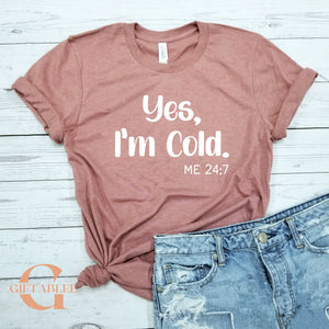A pink t-shirt with the text "Yes, I'm Cold. ME 24:7" printed on it, along with a pair of blue jeans.