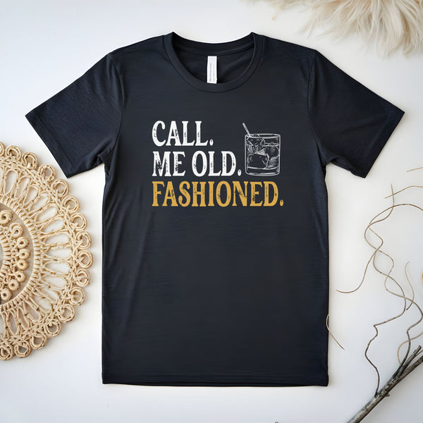 A black t-shirt with the text "CALL ME OLD, FASHIONED" printed on it, along with a graphic of a cocktail glass.