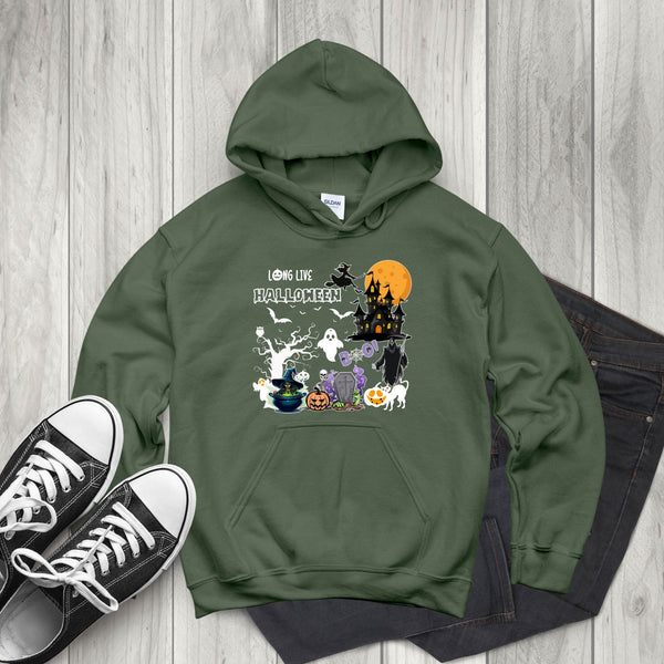 A green hoodie with a Halloween-themed graphic design, including a castle, ghost, pumpkin, and other spooky elements, is displayed on a wooden surface alongside a pair of black and white sneakers.
