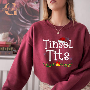 A woman wearing a red sweater with the text "Tinsel Tits" printed on it.