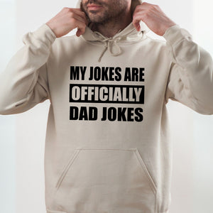 A man wearing a white hoodie with the text "MY JOKES ARE OFFICIALLY DAD JOKES" printed on it.