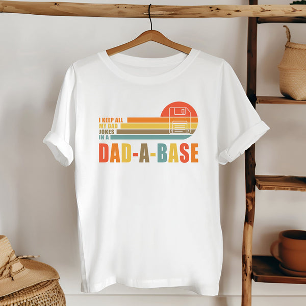 A white t-shirt with a graphic design and text printed on it, hanging on a wooden hanger.