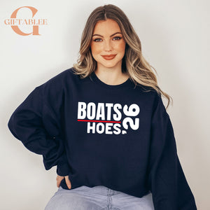 A woman wearing a navy blue sweatshirt with the text "BOATS Hoes" printed on it.