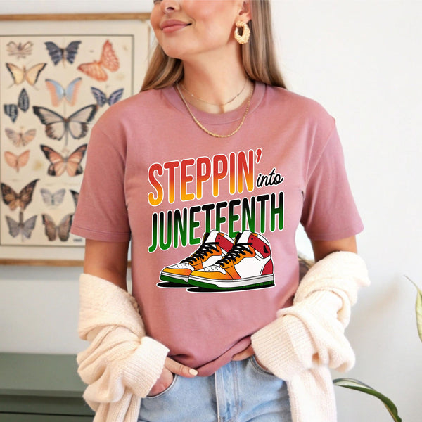 A woman wearing a pink t-shirt with a graphic design and text, standing in front of a butterfly-themed poster.