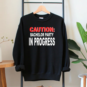 A black sweatshirt with a humorous text printed on it, hanging on a wooden hanger.